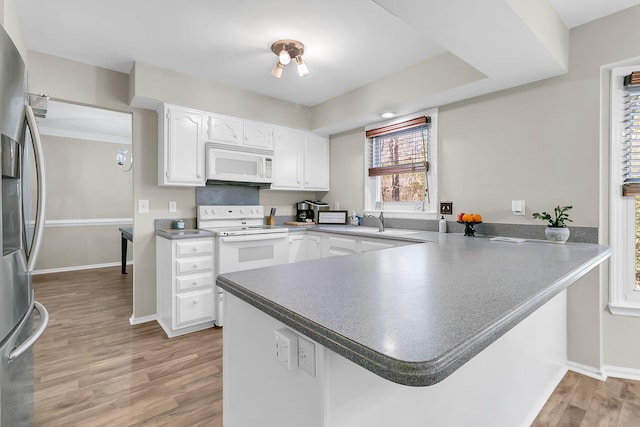 kitchen featuring white cabinetry, white appliances, and kitchen peninsula