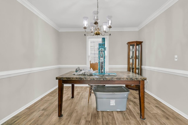 dining area with hardwood / wood-style flooring, ornamental molding, and an inviting chandelier