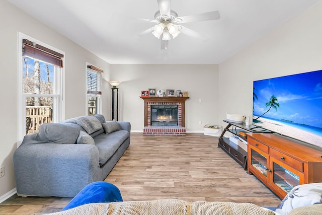 living room featuring a brick fireplace, ceiling fan, and light hardwood / wood-style flooring