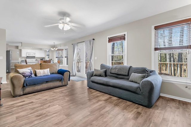 living room with ceiling fan with notable chandelier and light wood-type flooring