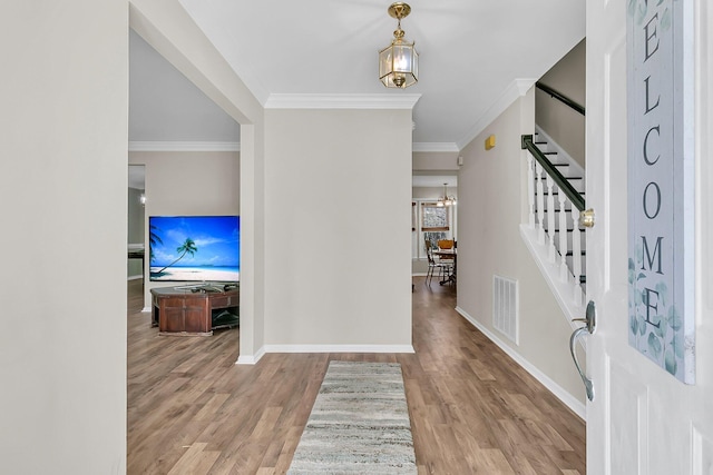 foyer entrance with ornamental molding and light hardwood / wood-style floors