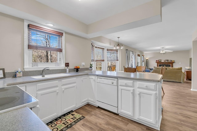 kitchen with decorative light fixtures, sink, white cabinets, kitchen peninsula, and white appliances