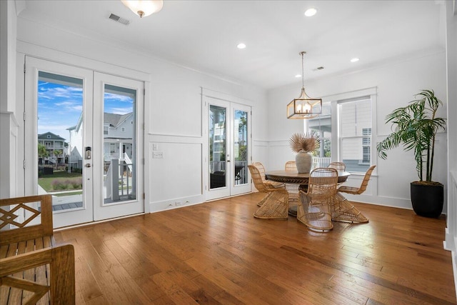 dining room with french doors, healthy amount of natural light, hardwood / wood-style floors, a decorative wall, and recessed lighting