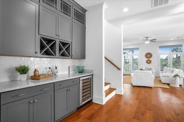 bar with gray cabinetry, dark hardwood / wood-style flooring, wine cooler, and french doors