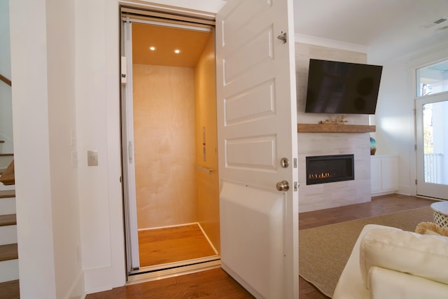 living room with a fireplace, wood finished floors, stairway, recessed lighting, and elevator