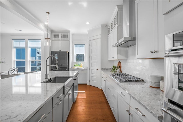 kitchen with wall chimney exhaust hood, tasteful backsplash, light stone counters, dark hardwood / wood-style floors, and pendant lighting