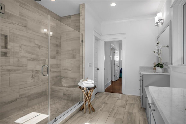 bathroom with vanity, a shower stall, recessed lighting, ornamental molding, and baseboards
