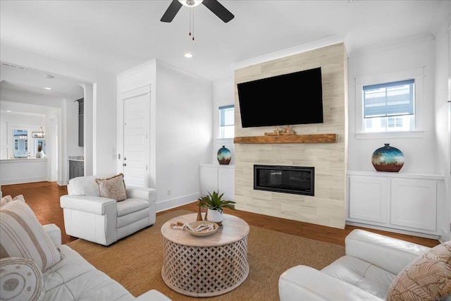 living room with a tiled fireplace, ceiling fan, and light hardwood / wood-style floors