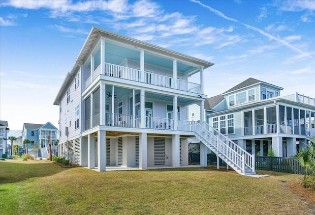 rear view of house with a balcony, a yard, a sunroom, and stairs