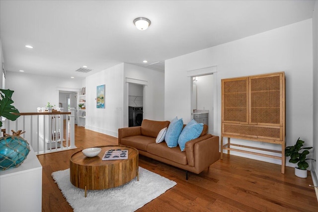 living area featuring washer / clothes dryer, wood finished floors, baseboards, and recessed lighting