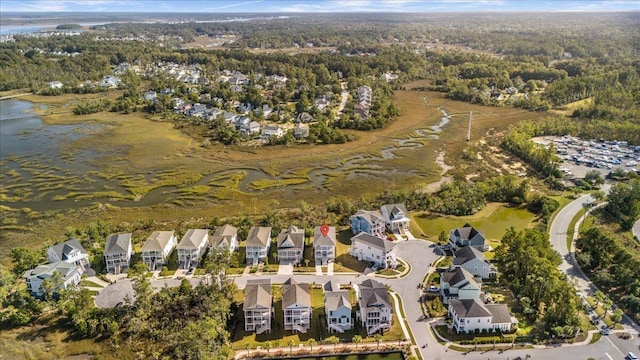 aerial view of property's location featuring a large body of water, nearby suburban area, and a forest