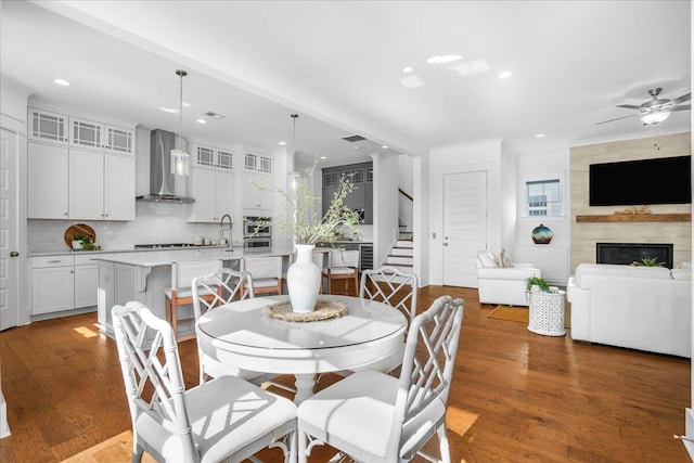 dining area with stairs, recessed lighting, wood finished floors, ceiling fan, and a fireplace
