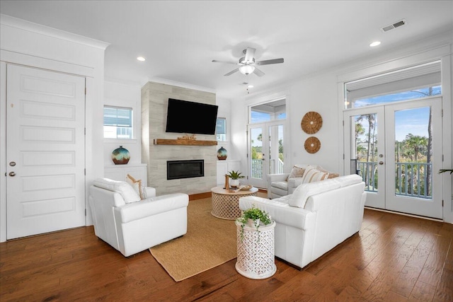living room with french doors, a ceiling fan, ornamental molding, plenty of natural light, and a tile fireplace