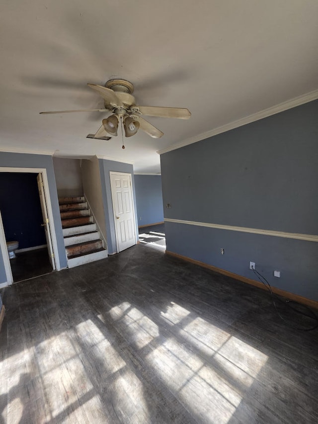 spare room featuring crown molding, stairway, a ceiling fan, wood finished floors, and baseboards