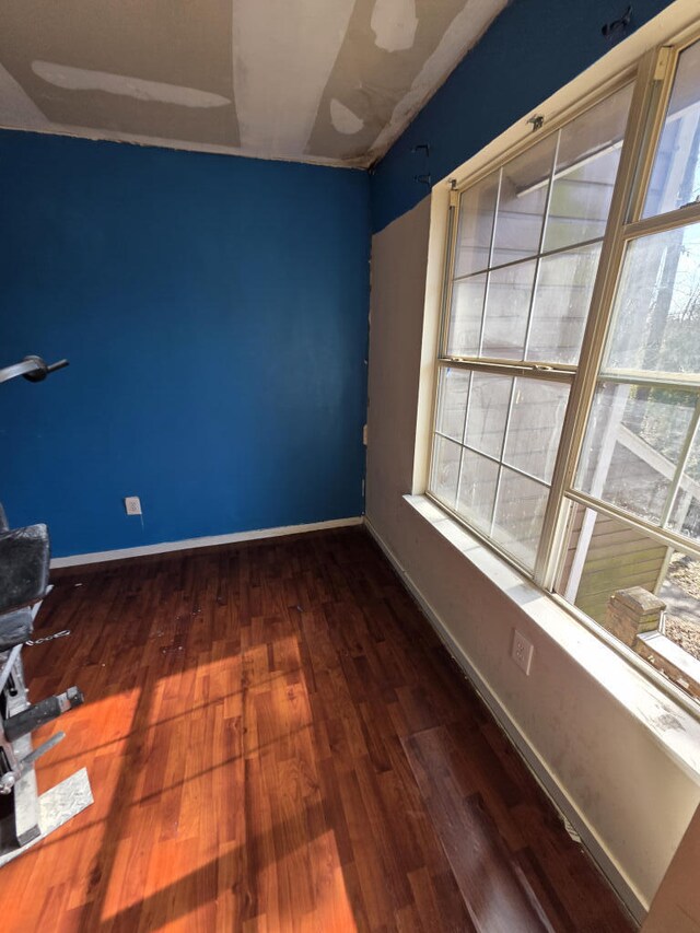 spare room featuring baseboards and wood finished floors