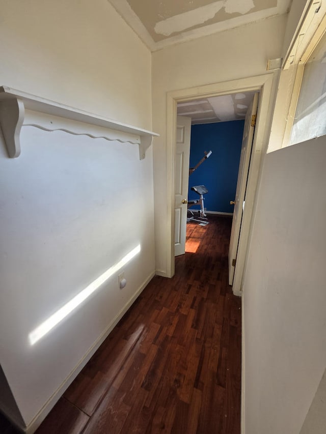 hallway featuring baseboards and dark wood-style flooring