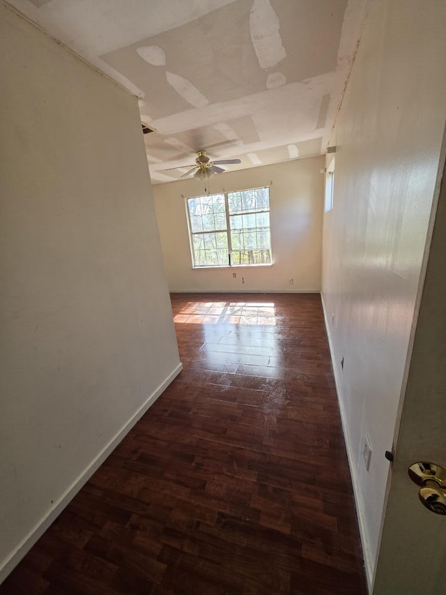 empty room featuring wood finished floors, a ceiling fan, and baseboards