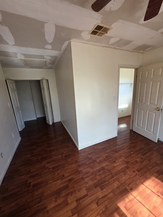 spare room with ceiling fan, dark wood-type flooring, visible vents, baseboards, and attic access