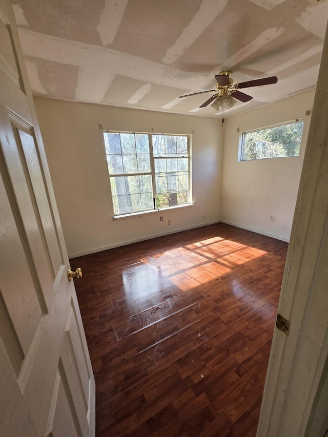 spare room featuring dark wood-type flooring, ceiling fan, and baseboards