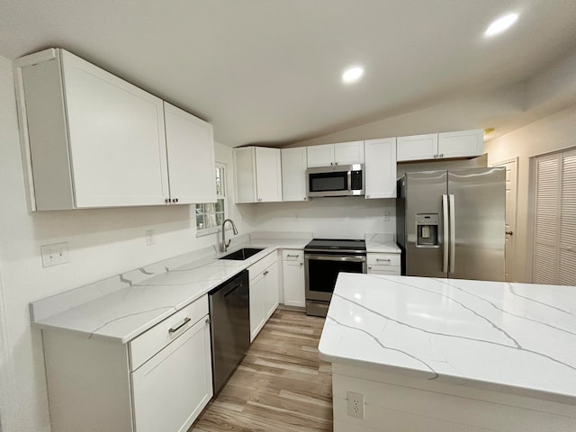 kitchen with appliances with stainless steel finishes, light stone countertops, sink, and white cabinets