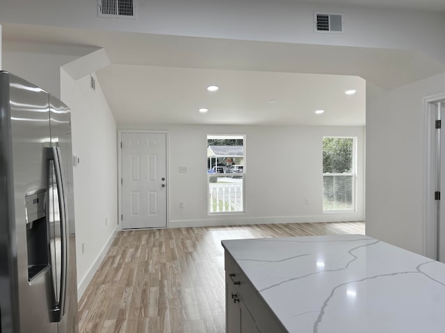 kitchen featuring light stone counters, stainless steel fridge, and light hardwood / wood-style floors