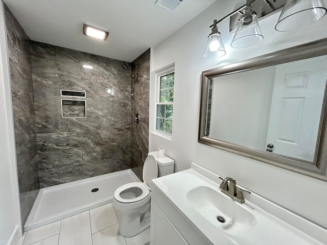 bathroom with vanity, tile patterned floors, toilet, and tiled shower