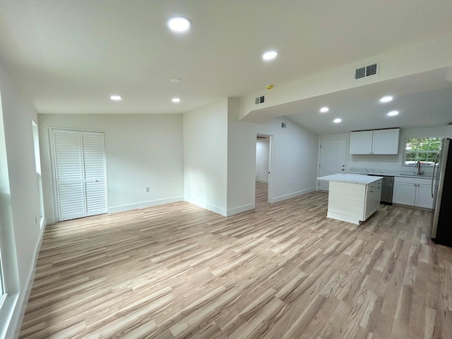 kitchen with sink, appliances with stainless steel finishes, a center island, white cabinets, and light wood-type flooring