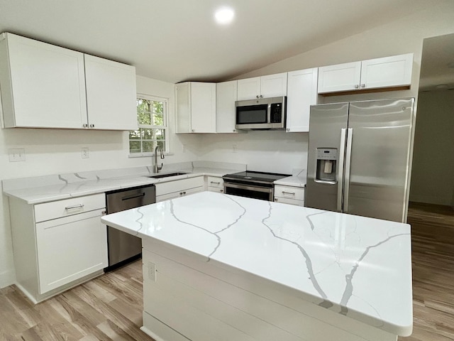 kitchen with light stone counters, vaulted ceiling, white cabinets, and appliances with stainless steel finishes