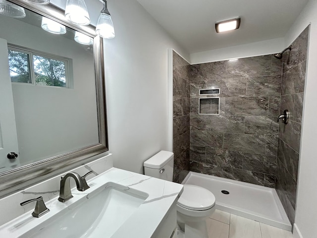 bathroom featuring vanity, tile patterned floors, toilet, and a tile shower