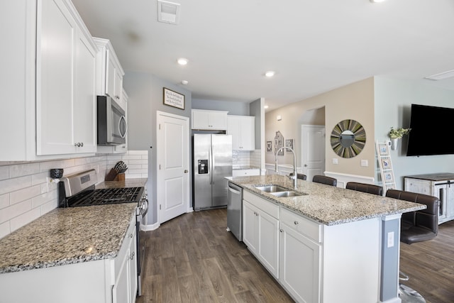 kitchen with appliances with stainless steel finishes, dark wood finished floors, white cabinetry, and a sink