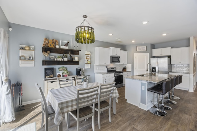 kitchen with white cabinets, appliances with stainless steel finishes, dark wood-style flooring, and a sink