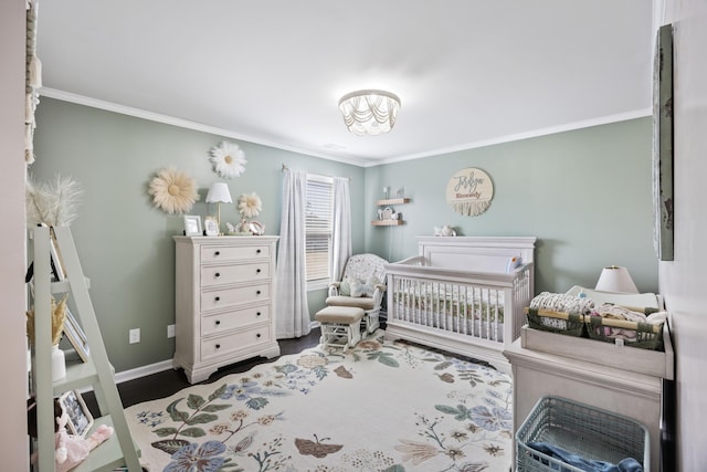 bedroom featuring ornamental molding, a crib, and wood finished floors