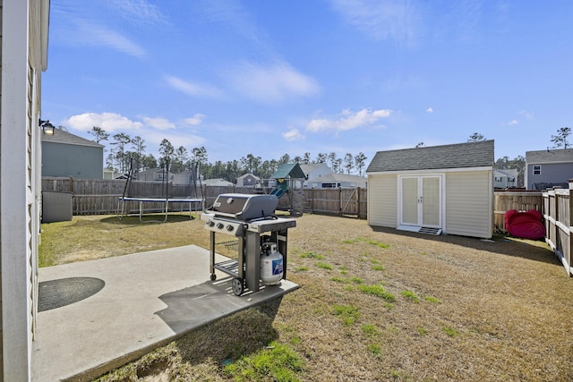 view of yard featuring a fenced backyard, a trampoline, a storage unit, an outdoor structure, and a patio area