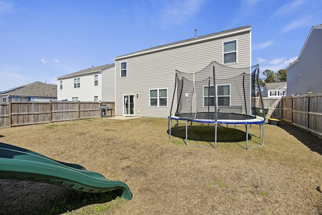 back of property featuring a yard, a trampoline, a playground, and a fenced backyard