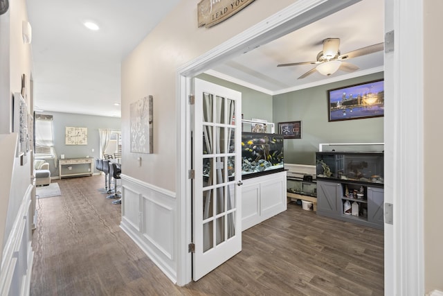 hallway with dark wood-style floors, crown molding, recessed lighting, a decorative wall, and wainscoting