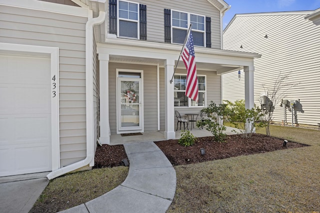 view of exterior entry with a garage and a porch