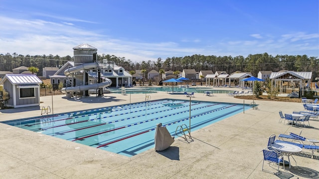 pool featuring a gazebo, fence, a water slide, and a patio