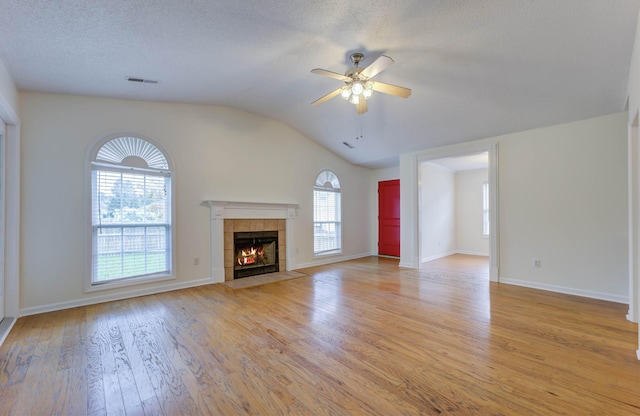 unfurnished living room featuring a ceiling fan, visible vents, a fireplace, light wood finished floors, and lofted ceiling