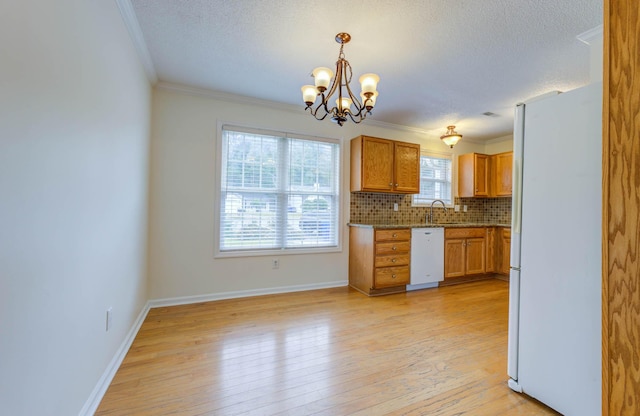 kitchen featuring a textured ceiling, a sink, light wood finished floors, an inviting chandelier, and white appliances
