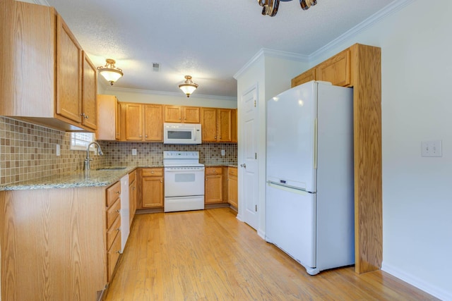 kitchen featuring tasteful backsplash, light stone countertops, a sink, light wood-style floors, and white appliances