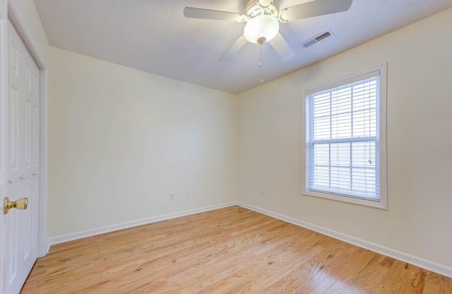 spare room featuring visible vents, light wood-style floors, ceiling fan, and baseboards