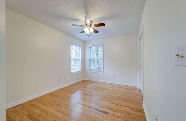 empty room featuring light wood-type flooring, a ceiling fan, a textured ceiling, and baseboards