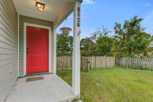 entrance to property featuring a lawn and fence