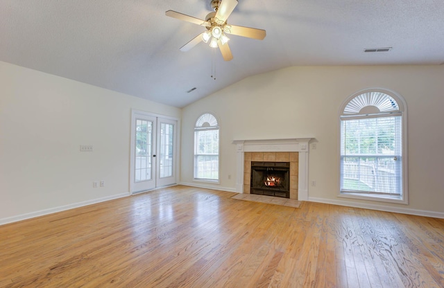 unfurnished living room with visible vents, lofted ceiling, a fireplace, ceiling fan, and light wood-type flooring