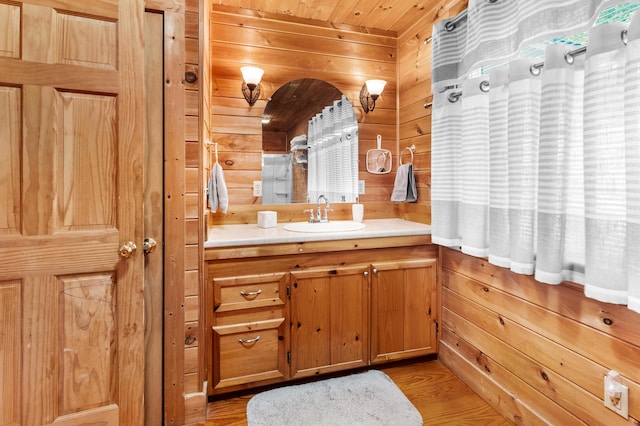 bathroom with wood ceiling, wooden walls, vanity, and wood finished floors