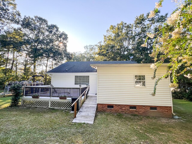 back of house with crawl space, roof with shingles, a lawn, and a wooden deck