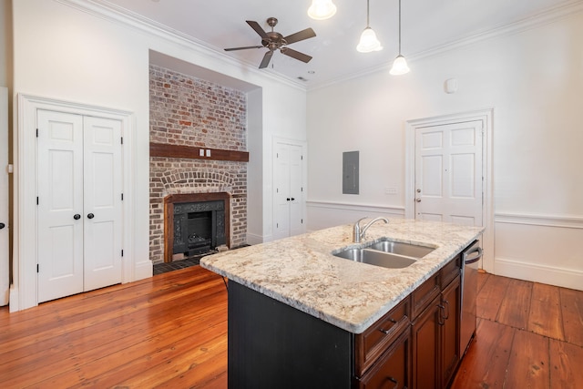 kitchen featuring ceiling fan, light hardwood / wood-style floors, sink, a fireplace, and a center island with sink