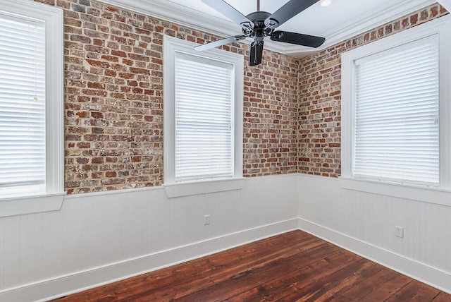 unfurnished room with brick wall, hardwood / wood-style flooring, crown molding, and ceiling fan