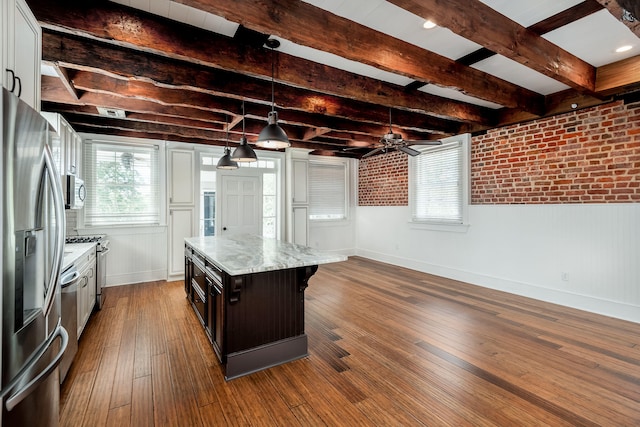 kitchen featuring decorative light fixtures, ceiling fan, a kitchen island, appliances with stainless steel finishes, and dark wood-type flooring