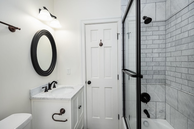 full bathroom with vanity, bath / shower combo with glass door, and toilet